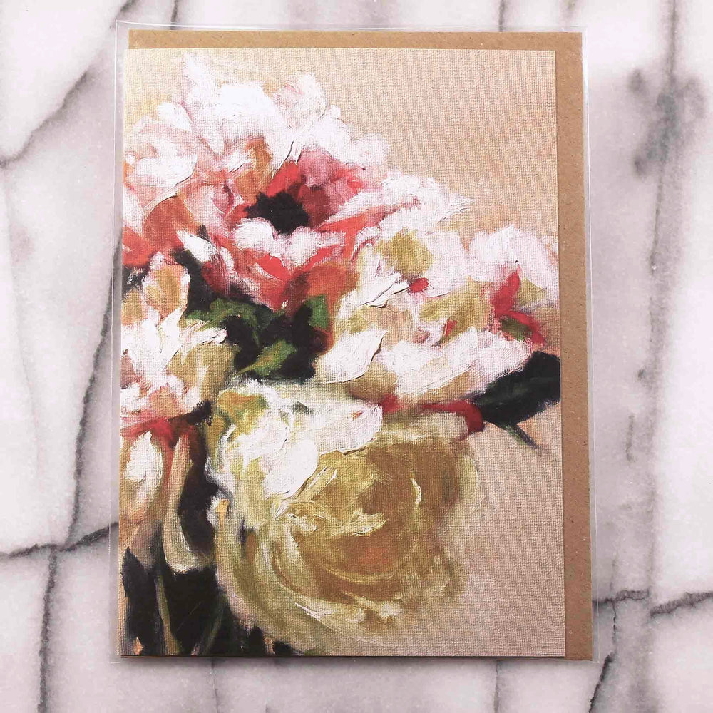 
                  
                    Load image into Gallery viewer, Poppies and Peonies Greeting Card presents an elegant and dreamy floral bouquet of pastel pinks, coral, cream and yellow with leafy accents that rests against a light peach background.  7&amp;quot; x 5”, front view presented with Kraft envelope inside protective plastic sleeve.
                  
                